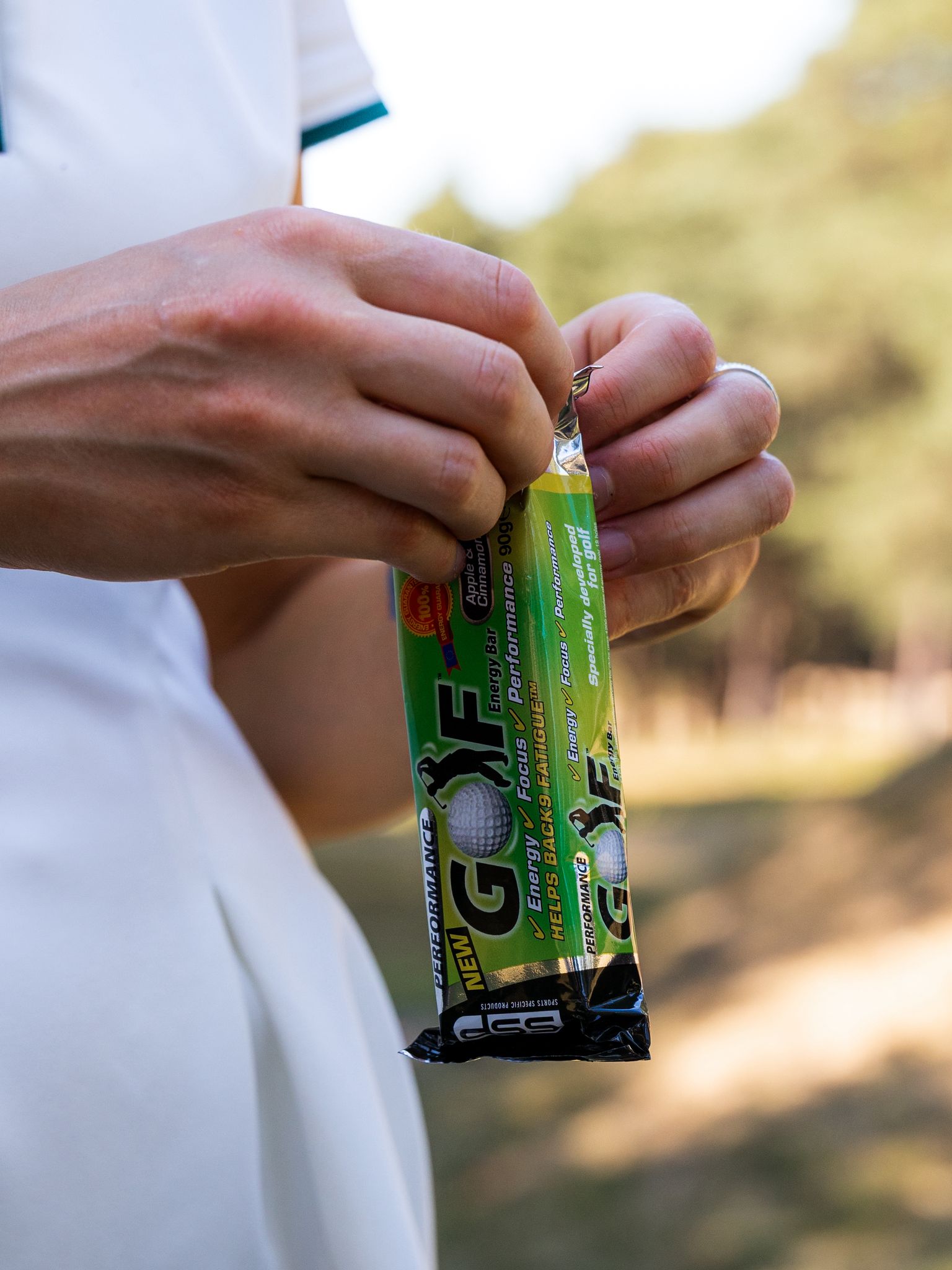 Golfer opening an SSP Golf energy bar on the course